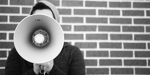 man holding megaphone in front of brick wall