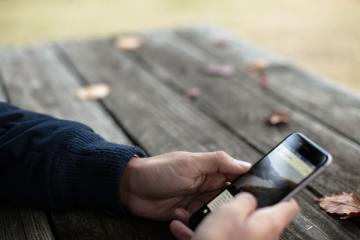 man at picnic table with smart phone