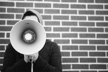 man holding megaphone in front of brick wall